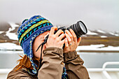 Amy Cadge, staff member from the Lindblad Expedition ship National Geographic Explorer taking a photograph with a camera in the Svalbard Archipelago, Norway, Arctic, Europe