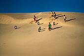 Children rolling tyres as hoops down the Nam Cuong sand hill in Ninh Thuan, Vietnam, Indochina, Southeast Asia, Asia