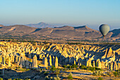 Aerial view of hot air balloon over rock formations in Love Valley at sunrise, Goreme, Goreme Historical National Park, UNESCO Worrld Heritage Site, Cappadocia, Central Anatolia Region, Anatolia, Turkey, Asia Minor, Asia