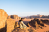 Mann genießt den Sonnenuntergang in der Wüste Wadi Rum,UNESCO-Welterbe,Jordanien,Naher Osten