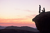 Two women sitting on a rock enjoying sunset in the desert of Wadi Rum, Jordan, Middle East