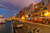 View of shops and restaurants in the fishing port Marina Grande with trail lights at dusk, Procida, Phlegraean Islands, Gulf of Naples, Campania, Southern Italy, Italy, Europe