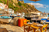 View of restaurant and boats in Marina di Corricella and fortress in background, Procida, Phlegraean Islands, Gulf of Naples, Campania, Southern Italy, Italy, Europe