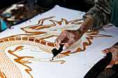 Woman using hot wax to outline a dragon design, Batik production, Yogyakarta, Java, Indonesia, Southeast Asia, Asia, Asia