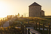 Ein Tourist beobachtet den Sonnenuntergang an den Windmühlen von Apulien im Sommer,Apulien,Esposende,Braga,Norte,Portugal,Europa