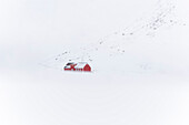 Eine rote Rorbu im Schnee am Skagsanden Strand,Flakstad,Flakstadoya,Nordland,Lofoten,Norwegen,Europa