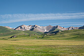 Weite grüne Wiesen treffen auf majestätische Berge am Song-Kol-See unter einem klaren blauen Himmel,Kirgisistan,Zentralasien,Asien