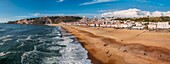 Aerial drone panoramic view of Nazare coastline showcasing beautiful beach, vibrant surf and rocky pier, Nazare, Oeste, Estremadura, Portugal, Europe