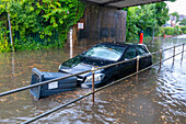 Flooded street with floating bin stuck in front of car, Sutton Coldfield, England, United Kingdom, Europe