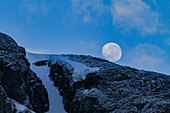 View of the nearly full moon rising over snow-covered mountains on the Antarctic Peninsula, Antarctica, Polar Regions