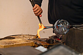 The glassblower shapes a spout for the pitcher with jacks in a glassblowing demonstration in Venice, Italy.