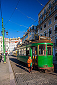 Lisbon, Portugal, March 1 2007, A vintage tram arrives at Figueira Square as a woman steps off onto the cobblestone street in Lisbon, showcasing urban life.