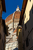 The dome of the Duomo in Florence, Italy, viewed down a narrow street.