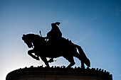 The majestic silhouette of the equestrian statue of King Dom Joao I stands prominently in Praca da Figueira, Lisbon, during sunset.