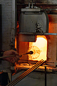 The glassblower reinserts the piece into the furnace in a glassblowing demonstration in Venice, Italy.