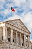 The grand facade of Sao Bento Palace stands proudly in Lisbon, showcasing neoclassical architecture under a blue sky.