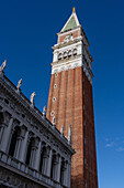 The campanile or bell tower of the Patriarchal Cathedral Basilica of Saint Mark or St. Mark's Basilica in Venice, Italy. At left is the Marciana National Library.