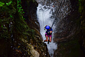 Young caucasian woman canyoning and rappelling in Costa Rica