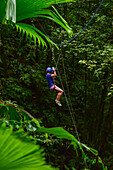 Young caucasian woman canyoning and rappelling in Costa Rica