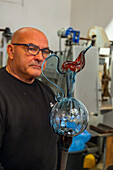 The glassblower with the completed pitcher in a glassblowing demonstration in Venice, Italy.