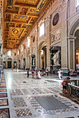 Rome, Italy, July 22 2017, Visitors admire the ornate architecture and sculptures inside San Giovanni in Laterano basilica, showcasing rich history and artistry.