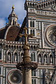 A carved stone cross on a pillar in front of the Duomo in Florence, Italy.