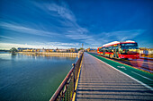 Seville, Spain, Jan 28 2021, A city bus crosses the historic Puente de Triana in Seville, offering a stunning view of the Guadalquivir River with Calle Betis in the background.