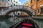 Gondolas carrying tourists pass under the Ponte Maria Callas bridge over a canal in Venice, Italy.