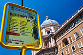 Visitors gather at the bus stop for the Christian Rome tour near the stunning Santa Maria Maggiore basilica under a clear sky.