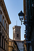 Giotto's Campanile or bell tower at the Duomo of Florence, Italy, framed down a narrow street.