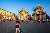 Rome, Italy, July 2017, Visitors enjoy a leisurely walk in Piazza del Popolo, surrounded by historic architecture as the sun sets in Rome.