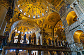 The silver and bronze crucifix on the Gothic altar screen in St. Mark's Basilica in Venice, Italy. On either side are statues of the Virgin and the Twelve Apostles.