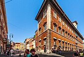 Rome, Italy, July 2017, Visitors stroll along Via del Corso, admiring the unique structure of Palazzo Ruspoli on a sunny day in Rome.