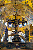 The silver and bronze crucifix on the Gothic altar screen in St. Mark's Basilica in Venice, Italy. On either side are statues of the Virgin and the Twelve Apostles.