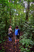 George of the Cloud Forest, guide and specialist, guides a young woman through Monterey cloud forest during fauna tour, Costa Rica