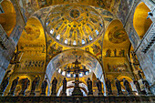 The silver and bronze crucifix on the Gothic altar screen in St. Mark's Basilica in Venice, Italy. On either side are statues of the Virgin and the Twelve Apostles.