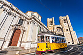 Lisbon, Portugal, March 1 2007, A yellow tram travels past the historic San Antonio de Lisboa church and the majestic Lisbon cathedral in the heart of the city.