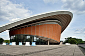 The House of World Cultures in Berlin features its iconic, curvilinear design amidst a scenic urban landscape.