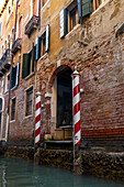 Eingang eines verwitterten Gebäudes entlang eines Kanals in Venedig,Italien.