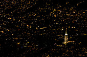 A church stands out among the city lights in one of the many poorer mountain barrios of Medellin, Colombia