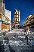 Sevilla,Spanien,28. Januar 2021,Eine lebhafte Straßenszene in der Calle San Pablo in Sevilla mit dem neobarocken Angel Sanz-Gebäude des Architekten Juan Talavera y Heredia und einem Passanten,der unter einem klaren blauen Himmel spazieren geht.