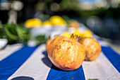 A close up image of a table with pomegranates and lemons, set outdoors at a vibrant wedding celebration in Malaga, Spain. Captures the freshness and festive atmosphere.