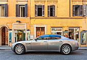 Eine elegante Luxuslimousine parkt vor einer Boutique in der Via Frattina im Zentrum Roms und zeigt die stilvolle Atmosphäre der Stadt.