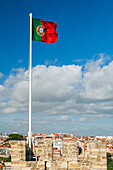 The Portuguese flag flutters above Lisbon, showcasing the city's beautiful skyline from the historic battlements of Saint George Castle.