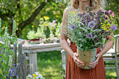 Woman holding a bouquet of flowers with fennel, oregano and mint