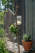 Mint, thyme, curry herb, oregano as a bouquet of herbs in a vase hanging on a branch with a tea light