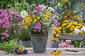 Summer bouquet of wild carrot, ornamental basket, globe thistle, fennel blossoms, scented nettle, dyer's chamomile in vase on garden table