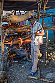Vendor roasting whole pigs over open fire