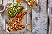 Chicken skewers with apple and sesame seeds, served with a side salad