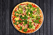 Pizza with ham, pickled gherkins, salad and barbecue sauce
